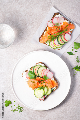 Healthy Scandinavian and Baltic  snack, lunch. Summer menu, Denmark. Smorrebrod, toasted bread with rye bread, salmon,curd cheese with herbs, green wild onion, cucumber and radish and microgreens