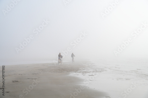 Fototapeta Naklejka Na Ścianę i Meble -  Fog on Baltic sea coastline at spring. Moody weather, mist. Cyclist riding in mist