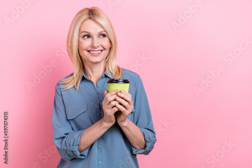 Photo portrait of cute lovely grandmother wear blue shirt hold coffee drink cup look empty space new property offer isolated on pink color background