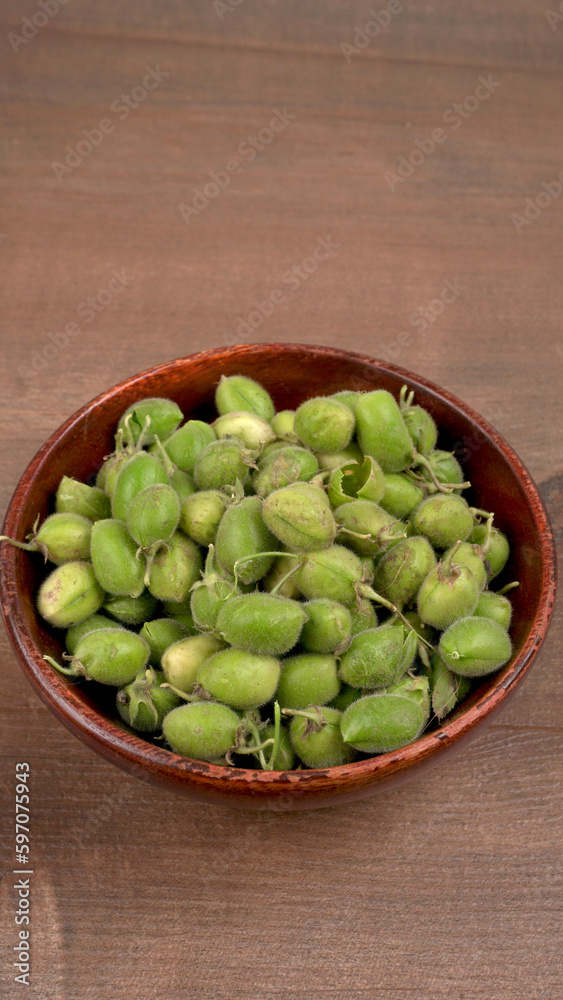 Fresh Green chickpeas on a branch, and in the pod, isolated on wooden background.