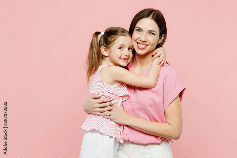 Happy smiling satisfied woman wear casual clothes with child kid girl 6-7 years old. Mother daughter hugging cuddling look camera isolated on plain pastel pink background. Family parent day concept. Happy smiling satisfied woman wear casual clothes with child kid girl 6-7 years old. Mother daughter hugging cuddling look camera isolated on plain pastel pink background. Family parent day concept.