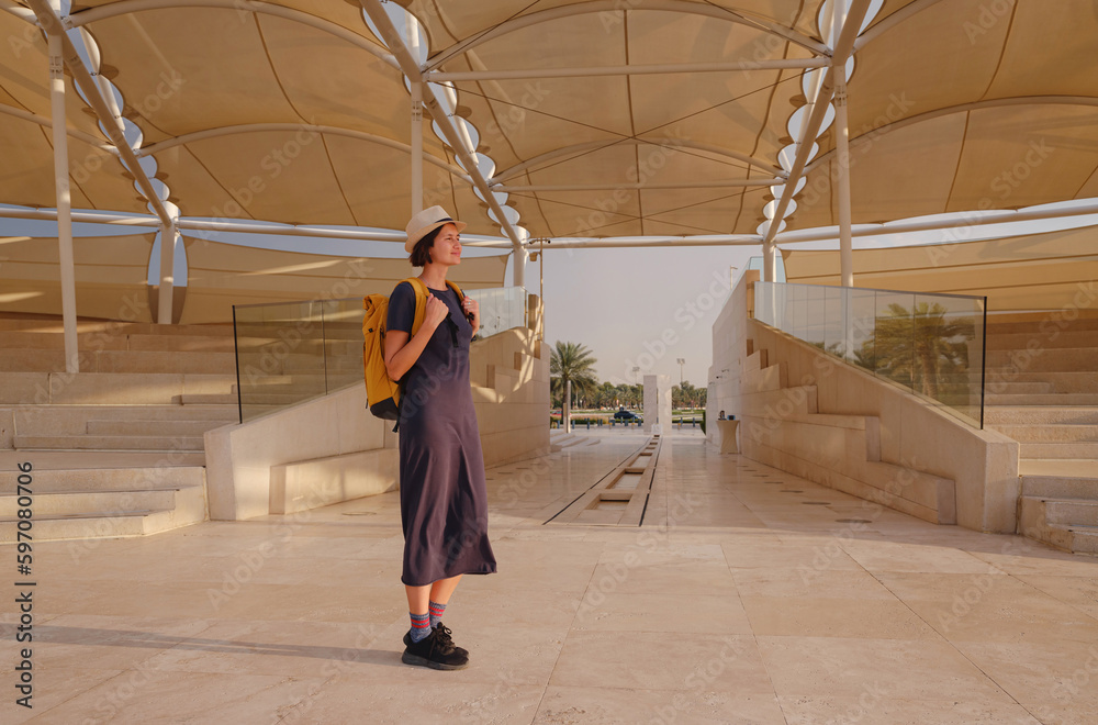 travel to the United Arab Emirates, Happy young asian female traveler with backpack and hat in Wahat Al Karama or Oasis of Dignity, permanent memorial for its martyrs, and Shaikh Zayed Grand Mosque. travel to the United Arab Emirates, Happy young asian female traveler with backpack and hat in Wahat Al Karama or Oasis of Dignity, permanent memorial for its martyrs, and Shaikh Zayed Grand Mosque.