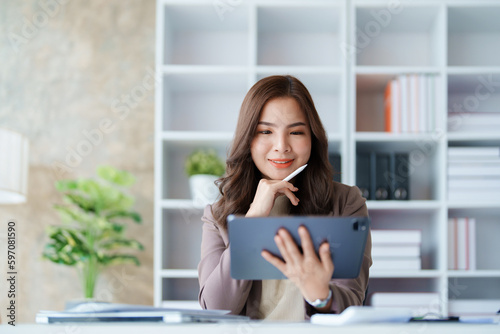 businesswoman in a black suit inside the office using tablet computer, audit paperwork for customers to contact, business people concept.