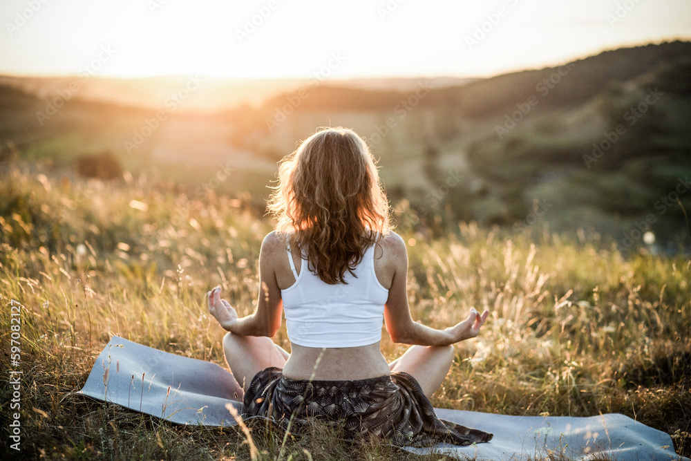 woman meditating outdoors at sunset