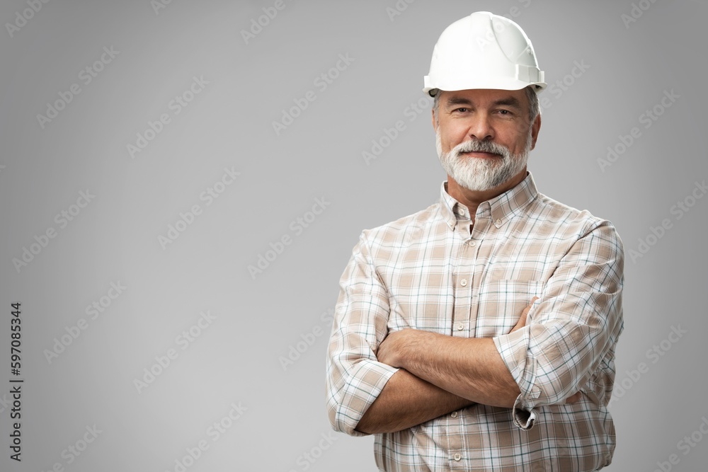 Portrait of happy mature architect in helmet standing with crossed arms. Male industrial inspector of 50s wearing uniform posing in studio Portrait of happy mature architect in helmet standing with crossed arms. Male industrial inspector of 50s wearing uniform posing in studio