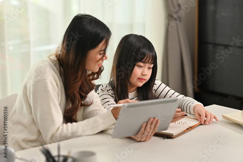 Interested Asian girl doing home working with tutor at home. Homeschooling and learning concept