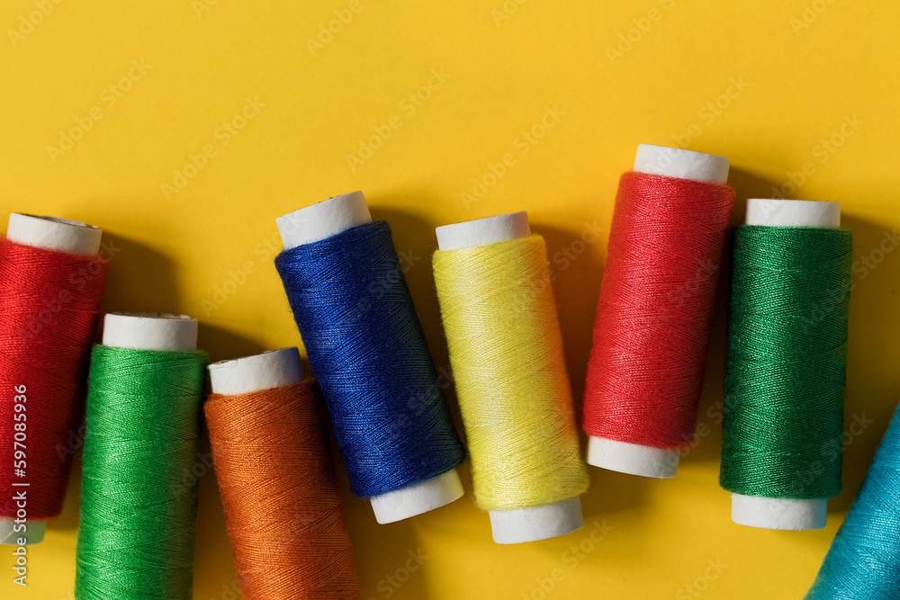 Colorful sewing threads on a yellow background. Top view. Copy space. Colorful sewing threads on a yellow background. Top view. Copy space.