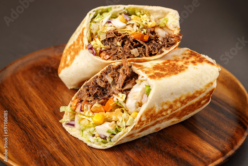 Burrito with pulled beef, Classic Mexican burrito with pulled chicken meat, black beans, pico de gallo and grilled wheat tortilla. photo