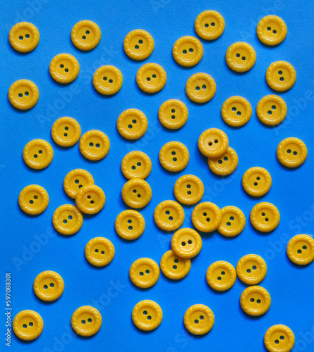 Blue background with yellow sewing buttons. Top view.