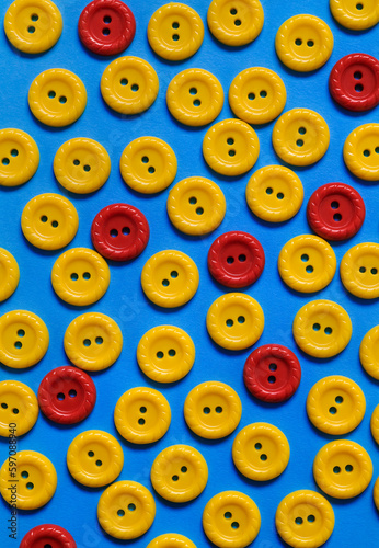 Yellow and red sewing plastic buttons on blue background. Creative concept. Top view.