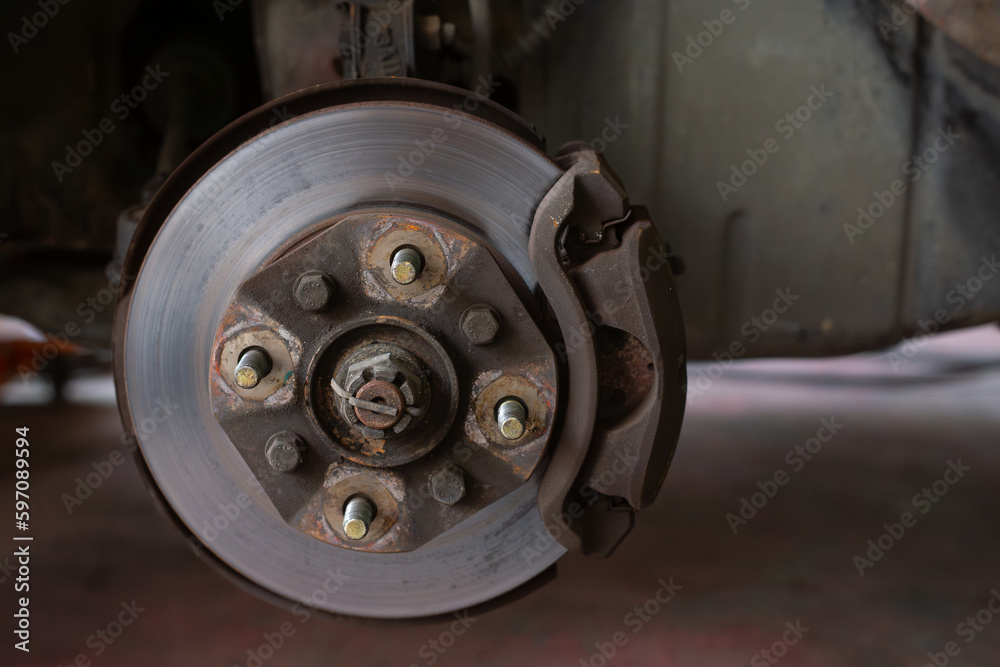 Brake discs, brake calipers and brake systems being maintained by a mechanic at a service center. Suspension of car for maintenance brakes and shock absorber systems.