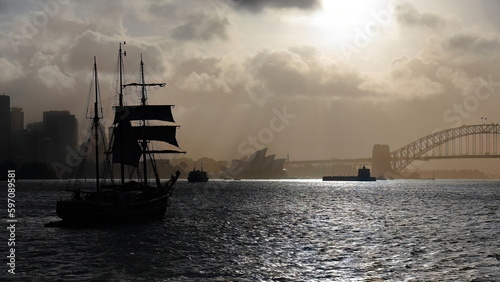 Silhouetted schooner barque tall ship sailing towards Harbour Bridge in a hazy afternoon. Sydney-Australia-562 photo