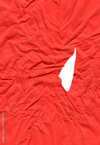 Red sheet of crumpled paper with an uneven tear in the center and multiple folds