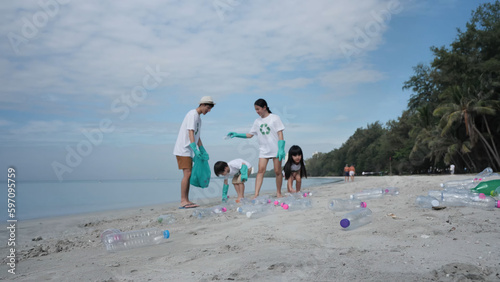 Plastic bottles on the beach in the background people out of focus are helping collect the plastic bottles off of the beach. Environmental Conservation Volunteer