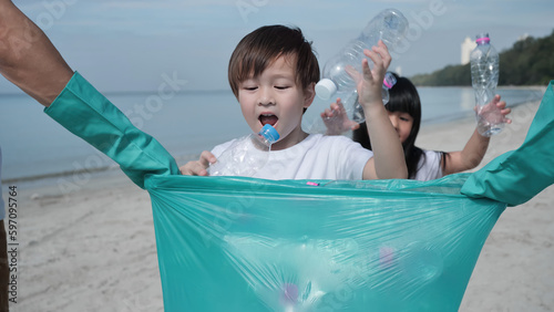 Close-up of Children is helping collect the plastic bottles into green plastic bag off of the beach. Environmental Conservation Volunteer