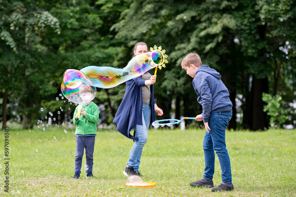 Fototapeta premium Mom and son are playing in the park. Cheerful happy family having a picnic. Vacations and trips out of town in country.