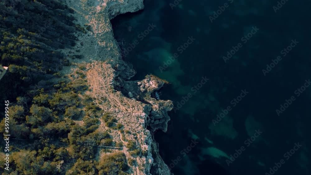 Sailing yacht boat in a remote bay, clear turquoise blue sea water, Palma de Mallorca Island. Seaside coast at Cala Mondrago. Spanish Balearic Majorca, cinematic ship vacation yachting aerial drone 4K