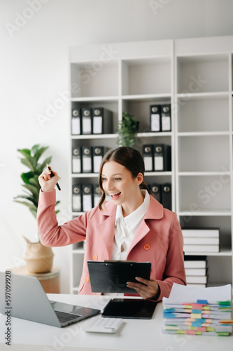 Caucasian business woman are delighted and happy with the work they do on their tablet, laptop and taking notes at the office.