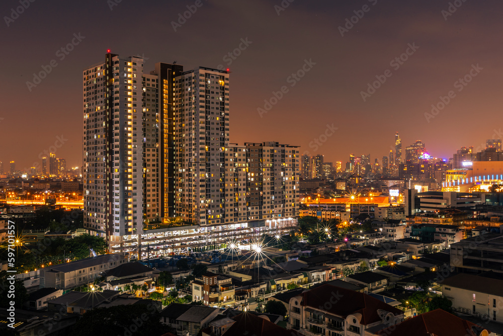 The high angle background of the city view with the secret light of the evening, blurring of night lights, showing the distribution of condominiums, dense homes in the capital community The high angle background of the city view with the secret light of the evening, blurring of night lights, showing the distribution of condominiums, dense homes in the capital community