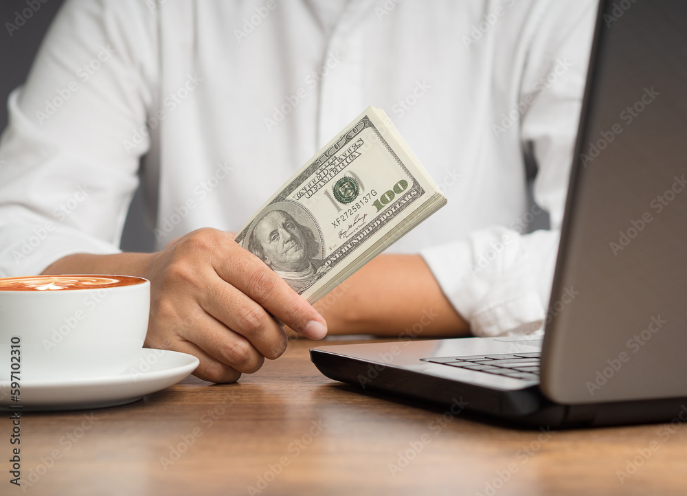 Personal loan concept. Businesswoman in a white shrit holding US dollar bills while sitting in the office Personal loan concept. Businesswoman in a white shrit holding US dollar bills while sitting in the office