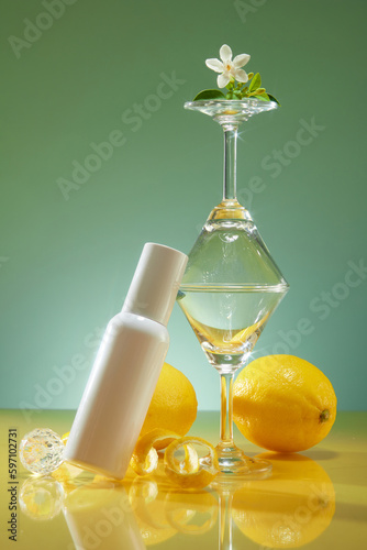 Template for cosmetic advertising with white bottle unlabeled beside are glass cups and fresh lemon  crystal ball decorated on green background. Lemon extract concept