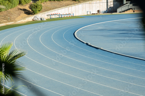 Pista de atletismo con curva carriles de distancia para practicar deporte en color azul. © Dani