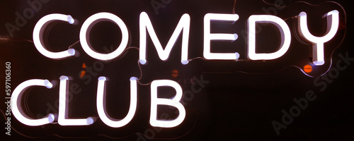 white neon sign advertising a comedy club