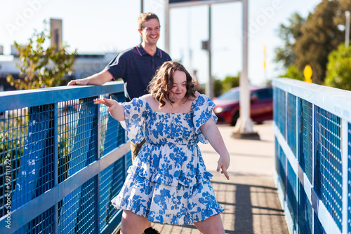 Happy teenage girl with down syndrome dancing on blue footbridge photo