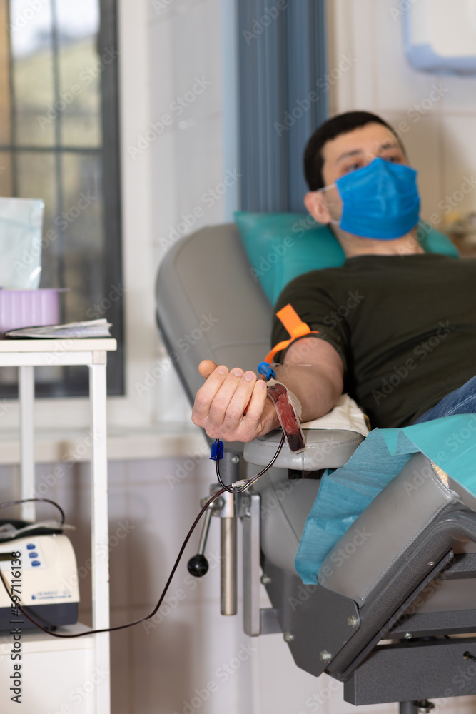 man donor in medical mask for bone marrow donation blood in laboratory. male hand holding red ball, prevention of diseases, illness hemodialysis transfusion in hospital. soft focus, vertical man donor in medical mask for bone marrow donation blood in laboratory. male hand holding red ball, prevention of diseases, illness hemodialysis transfusion in hospital. soft focus, vertical