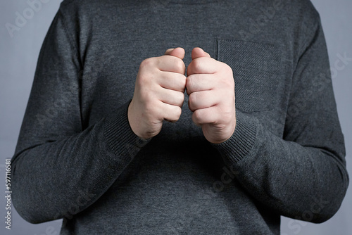 Young man's hands balled into fists in front of him. A sign of unpreparedness, reflection, doubt photo