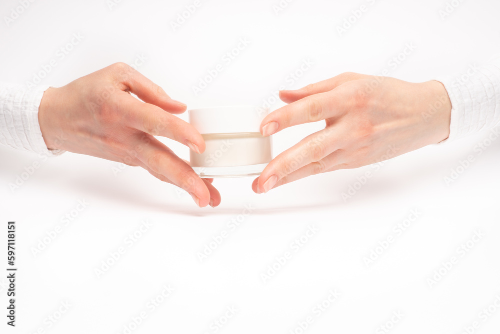 Mock-up of beautiful woman's hand holds round jar or container of cosmetic product cream or lotion on white isolated background. Concept of beauty, spa industry, skin care. Close-up, copy space