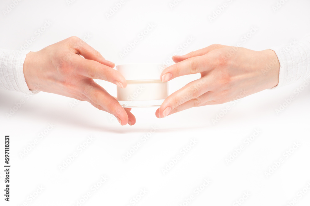 Mock-up of beautiful woman's hand holds round jar or container of cosmetic product cream or lotion on white isolated background. Concept of beauty, spa industry, skin care. Close-up, copy space