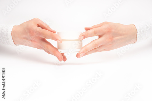 Obraz na płótnie Mock-up of beautiful woman's hand holds round jar or container of cosmetic product cream or lotion on white isolated background. Concept of beauty, spa industry, skin care. Close-up, copy space w salonie