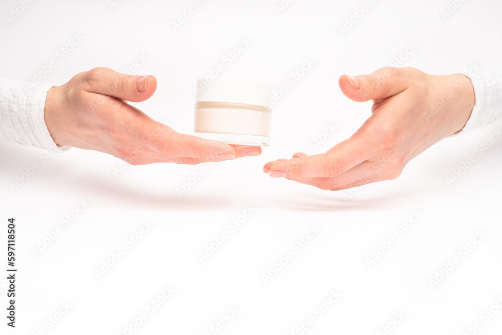 Mock-up of beautiful woman's hand holds round jar or container of cosmetic product cream or lotion on white isolated background. Concept of beauty, spa industry, skin care. Close-up, copy space