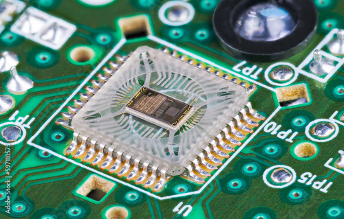 Closeup of microchip die inside optical sensor on green printed circuit board. Electronic square transparent surface mounted component to detect motion and round light source on PCB in computer mouse. photo