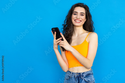 Cheerful woman use smartphone reading social network news follow repost wear style stylish trendy tank-top isolated over blue color background