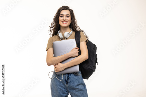 Portrait of a pretty cheerful girl carrying backpack standing isolated over white background, holding laptop computer