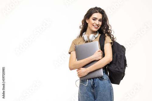 Portrait of a pretty cheerful girl carrying backpack standing isolated over white background, holding laptop computer