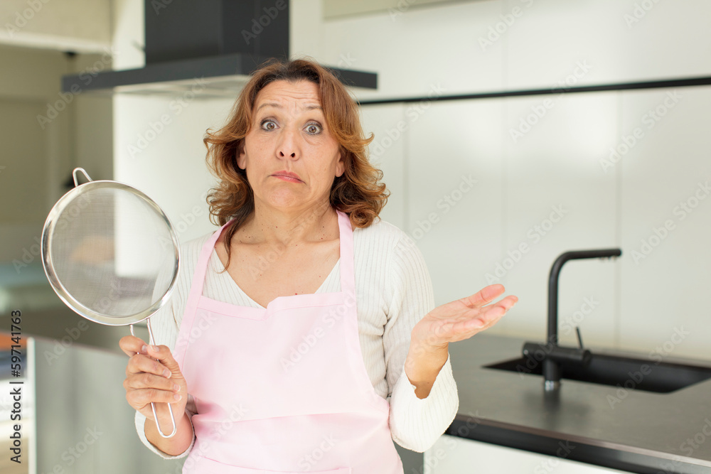 middle age pretty woman shrugging, feeling confused and uncertain. cooking at home concept