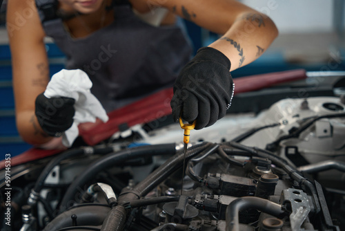 Car mechanic in protective gloves checks the oil level in car © Viacheslav Yakobchuk
