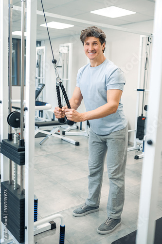 Smiling dark-haired man standing near training device