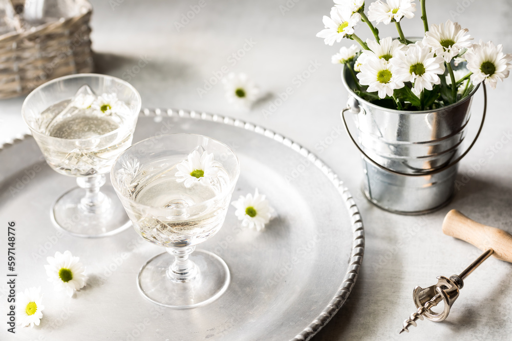 White wine on a silver tray with small white daisy blossoms.
