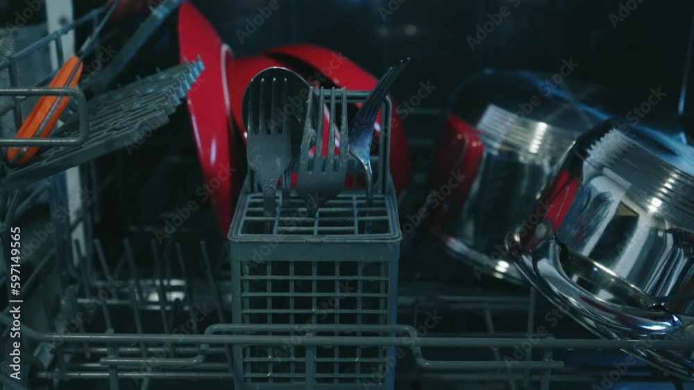 Loading dirty plates, crockery and glass into the dishwasher. Puts