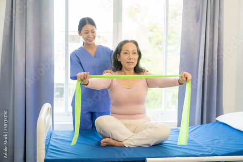 Happy senior woman exercising at home with muscle physiotherapist Retired elderly woman stretching arms and legs at home with personal trainer