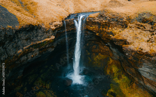 Kvernufoss waterfall in a mountain gorge. The amazing nature of Iceland. Wallpaper background of the wild icelandic nature.