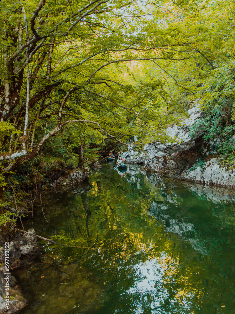 A group of friends enjoying having fun and kayaking while exploring the calm river, surrounding forest and large natural river canyons A group of friends enjoying having fun and kayaking while exploring the calm river, surrounding forest and large natural river canyons