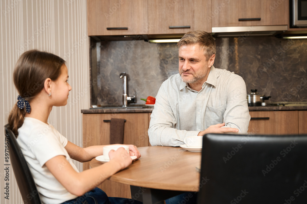 Handsome father and his daughter drinking tea in the kitchen in hotel room Handsome father and his daughter drinking tea in the kitchen in hotel room