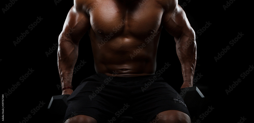 Muscular bodybuilder doing exercises with dumbbells on black background