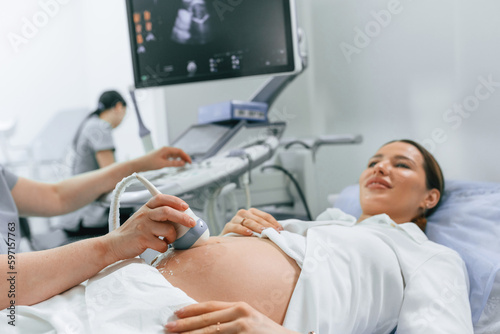 Close up view, scanning. Pregnant woman is lying down in the hospital, doctor does ultrasound
