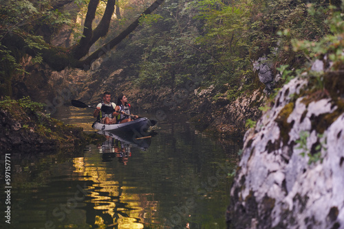 A young couple enjoying an idyllic kayak ride in the middle of a beautiful river surrounded by forest greenery